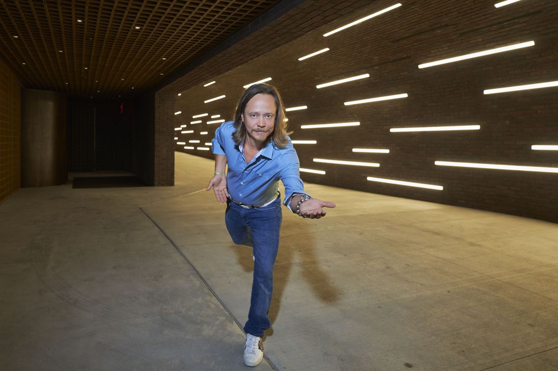 Brock Pierce balancing on one leg, arms out, in a tunnel lined with streaks of light